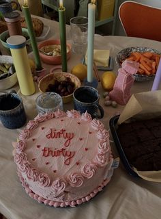 a birthday cake sitting on top of a table next to other foods and desserts