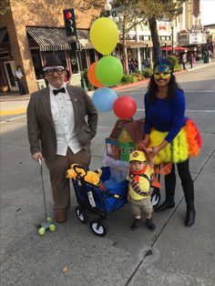 a man, woman and child dressed up in costumes standing on the street with balloons