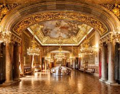 an ornate hall with chandeliers and paintings on the walls