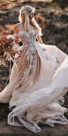 a woman in a wedding dress with flowers on her head is walking away from the camera