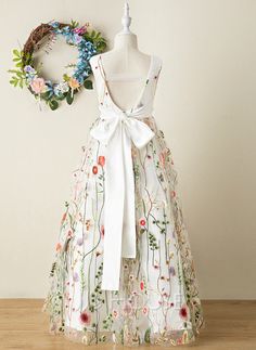 a white dress with flowers on it next to a wreath