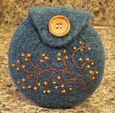 a blue purse with gold buttons is sitting on a granite countertop and has small leaves embroidered on it