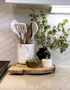 kitchen utensils are sitting on a cutting board in front of a potted plant