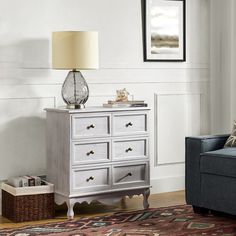 a living room with a blue couch and a white dresser next to a lamp on top of a rug