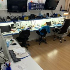 an office with multiple computers and monitors on the wall