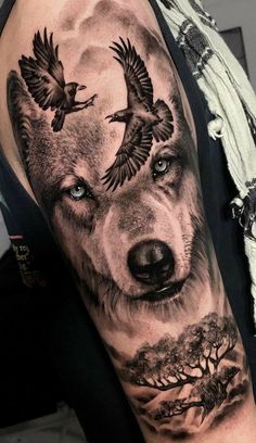 a man's arm with a wolf and two birds on it, in black and grey