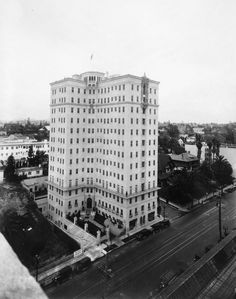 an old black and white photo of a large building in the middle of a city