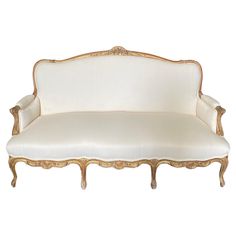 an antique style couch with gold trimmings and white upholstered fabric on the back