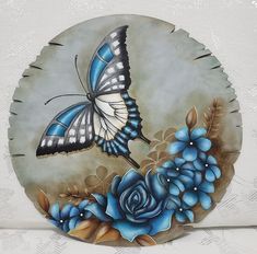 a blue and white plate with a butterfly on it's wings, surrounded by flowers