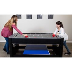 two girls playing air hockey on a coffee table in the living room with blue and black accents