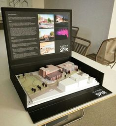 a model of a building on display in a case with information about the structure and its surroundings