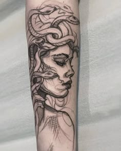 a woman's face and snake tattoo on the left arm, with black ink