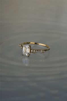 an engagement ring with a square cut diamond in the center, surrounded by water ripples