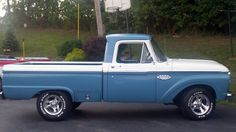 an old blue and white truck parked in a parking lot next to a basketball hoop