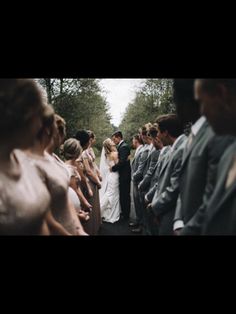 a group of people standing next to each other on top of a road with trees in the background