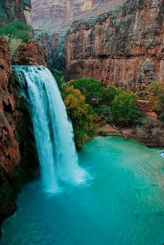 a large waterfall in the middle of a canyon with blue water flowing down it's sides