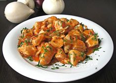 a white plate topped with chicken covered in sauce and garnished with parsley