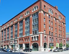 an old red brick building on the corner of a street with cars parked in front