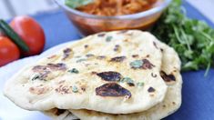 two pita breads on a plate with tomatoes and lettuce next to it