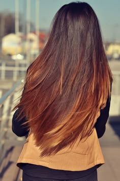 the back of a woman's head with long brown hair and black shirt on