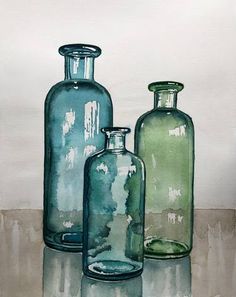 three green glass bottles sitting on top of a table