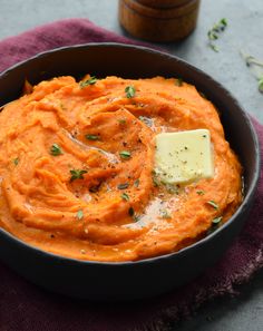 a bowl filled with mashed carrots and topped with a pate of butter