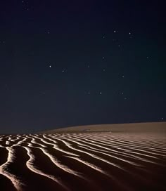 the night sky is lit up by stars above sand dunes