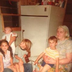 a group of people sitting on top of a bed next to a refrigerator freezer