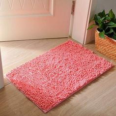 a pink rug on the floor in front of a door with a basket and potted plant