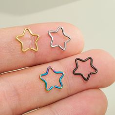 three star shaped studs in different colors on someone's finger with their fingers