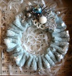 a knitted wreath with ornaments on top of sheet music