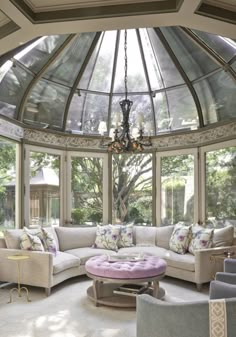 a living room filled with lots of furniture under a glass dome ceilinging over a large window