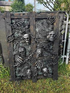 a large metal door with skulls and chains on it's sides in the grass