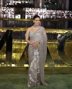 a woman in a silver sari standing next to a large sign that says love