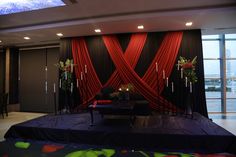 a stage set up with red drapes and black table cloths for an event