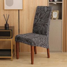 a black and white patterned chair sitting in front of a wooden shelf with pictures on it