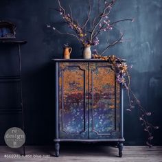 a blue cabinet with flowers and vases on it in front of a dark wall