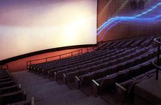 an empty auditorium with rows of seats and a projector screen on the wall behind it