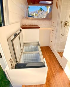 the inside of a small house with wood flooring and white walls, including an open refrigerator