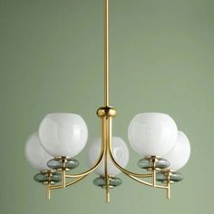 a brass chandelier with three white glass balls hanging from it's arms