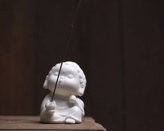 a small white statue with a needle sticking out of it's back end on a wooden table