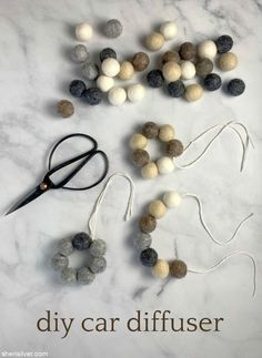 the diy car diffuser is made out of felt balls and yarn with scissors