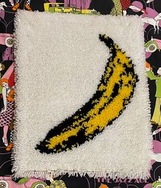 a yellow banana on a white rug in front of a black and pink background