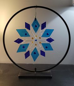 a blue and white snowflake is hanging from a black metal ring on a table