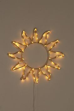 a lighted sunburst hanging on the wall with string lights attached to it's sides