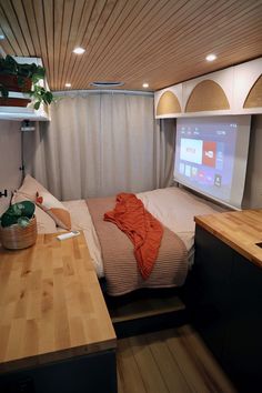 a bed sitting next to a wooden counter top in a bedroom under a projector screen