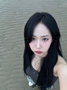 a woman with long black hair standing in the sand