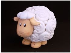 a small toy sheep with white hair on it's head and eyes, standing in front of a black background