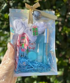 someone is holding up a clear bag filled with items for the holiday season in front of some trees