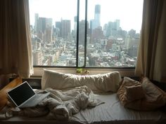 an open laptop computer sitting on top of a bed in front of a large window